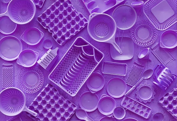 Close up flat lay of different purple violet color painted kitchen utensils and tools, grater, spoon, egg carton, plastic disposable plates, elevated top view, directly above