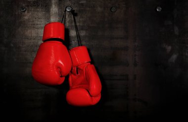 Siyah duvarda asılı kırmızı deri boks eldivenlerini kapatın.