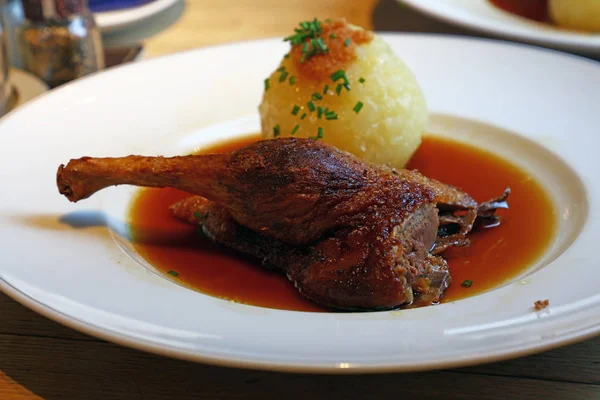 Ördek confit bacak soslu patates hamur tatlısı top ve bira, masada, yüksek açılı görünüş beyaz tabakta Bavyera Alman mutfağının geleneksel çanak kısmını kapatın