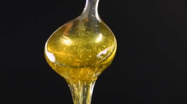 Akasya dökme tatlım ve yan görüş açısı düşük kopya alanı, siyah zemin üzerinde metal kaşık akan, yavaş hareket taze kalın sıvı kapatın