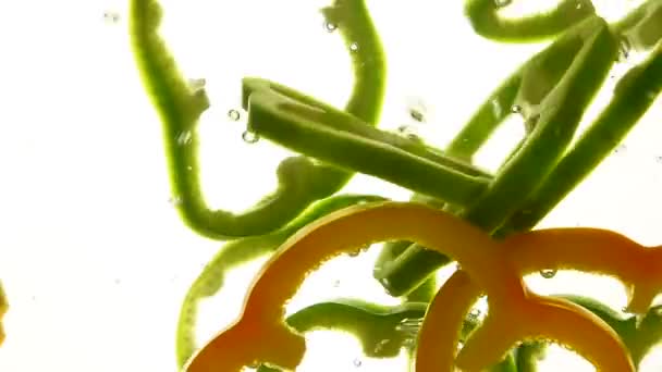 Fette di peperone giallo e verde galleggiano in acqua — Video Stock