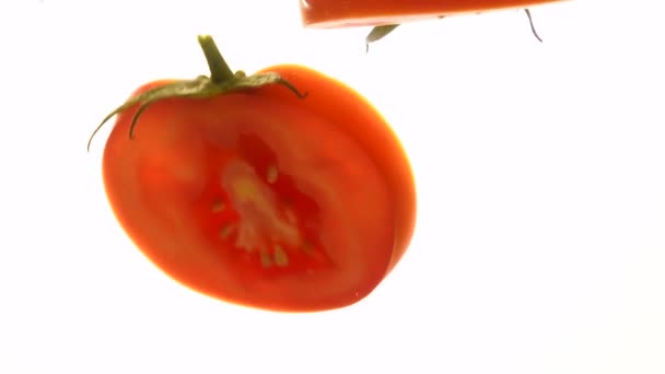 Snijd plakjes rode tomaten die in water zweven — Stockvideo