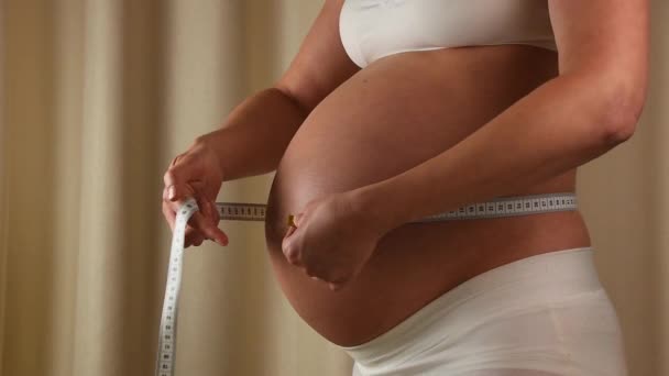 Έγκυος γυναίκα ελέγχει την κοιλιά της με ταινία μέτρησης — Αρχείο Βίντεο