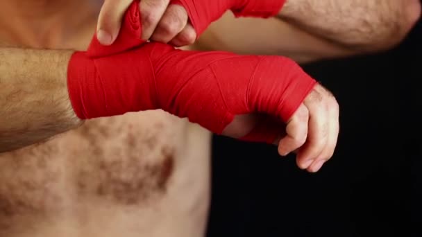 Cerca de hombre boxeador envolver muñecas con envoltura roja — Vídeo de stock