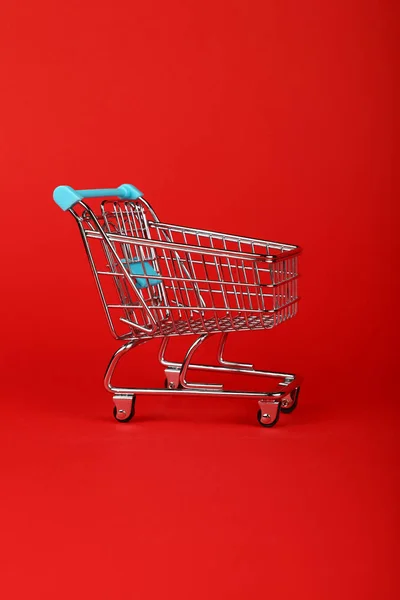Fechar carrinho de compras de varejo no fundo vermelho — Fotografia de Stock