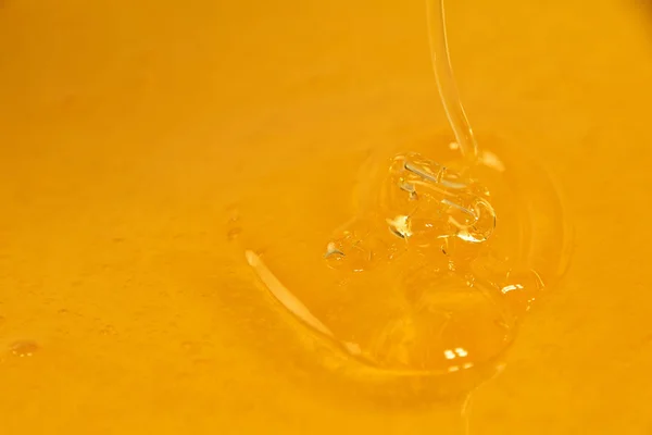Chiudere versando miele fresco fluido in ciotola — Foto Stock