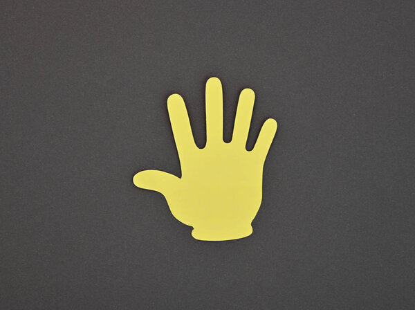 Paper made yellow STOP gesture sticker on grey