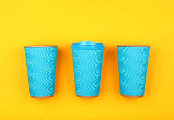 Three blue paper coffee cups over yellow — Stock Photo, Image