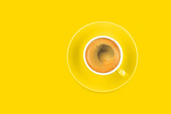 Ένα πλήρες φλιτζάνι καφέ εσπρέσο με πιατάκι σε κίτρινο — Φωτογραφία Αρχείου