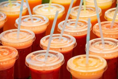 Birçok plastik bardakta taze meyve ve sebze suyu ve smoothie 'yi perakende satış mağazasında pipet içerek, yüksek açılı manzarayla kapatın.
