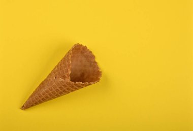 Sarı kağıt üzerinde boş bir dondurma külahını kapat, üst manzarası yüksek, tam üstte.