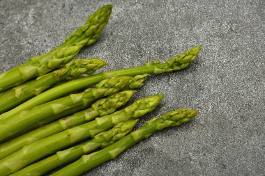 Kesme tahtasında ya da gri taş masa yüzeyinde yüksek açı manzaralı bir grup taze kuşkonmaz kapat.