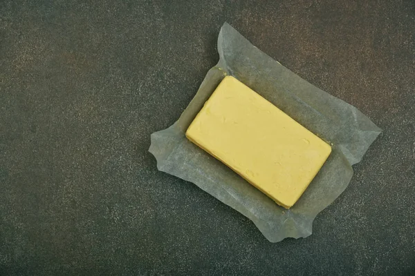 将新鲜的黄色硬牛油贴在纸上贴在烤好的桌子表面上 向上看 正上方 — 图库照片