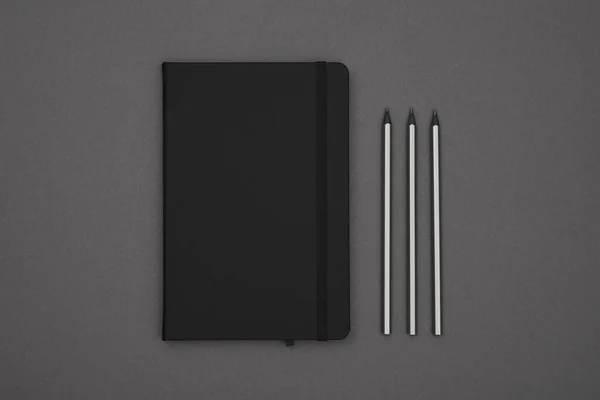 Zamknij Jeden Zamknięty Czarny Skórzany Notatnik Ołówki Szarym Papierowym Tle — Zdjęcie stockowe