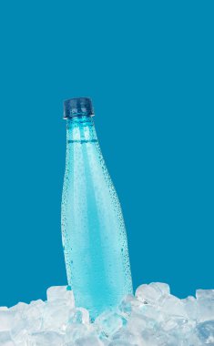 Bir tam PET plastik şişe soğuk hala içme suyu buz küpleri üzerinde soğutma mavi arka plan, düşük açı yan görünüm izole