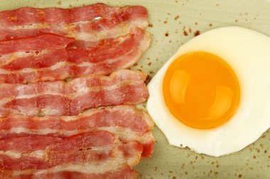 Yakın İngiliz kahvaltısı, güneşli yan yumurta ve kızarmış pastırma dilimleri mavi tabakta, üst manzarada, tam üstte.