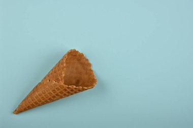 Pastel mavi kağıdın üzerinde boş bir dondurma külahını kapat. Üst manzarası yüksek, tam üstünde.