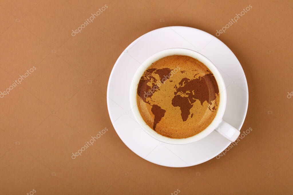 Close up white cup on saucer, full of espresso coffee with world map on froth crema, over background of brown paper with copy space, elevated top view, directly above