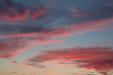 Mavi gökyüzü üzerinde kırmızı pofuduk gün batımı bulutları, alçak açı manzaralı güzel bulutlar.