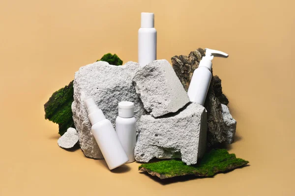Campione cosmetico bottiglia bianca incastonata su pietra, muschio, podio in legno su fondo beige. Occorrente per le vacanze — Foto Stock