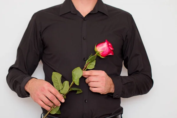 A man in a black shirt with a flower in his hands