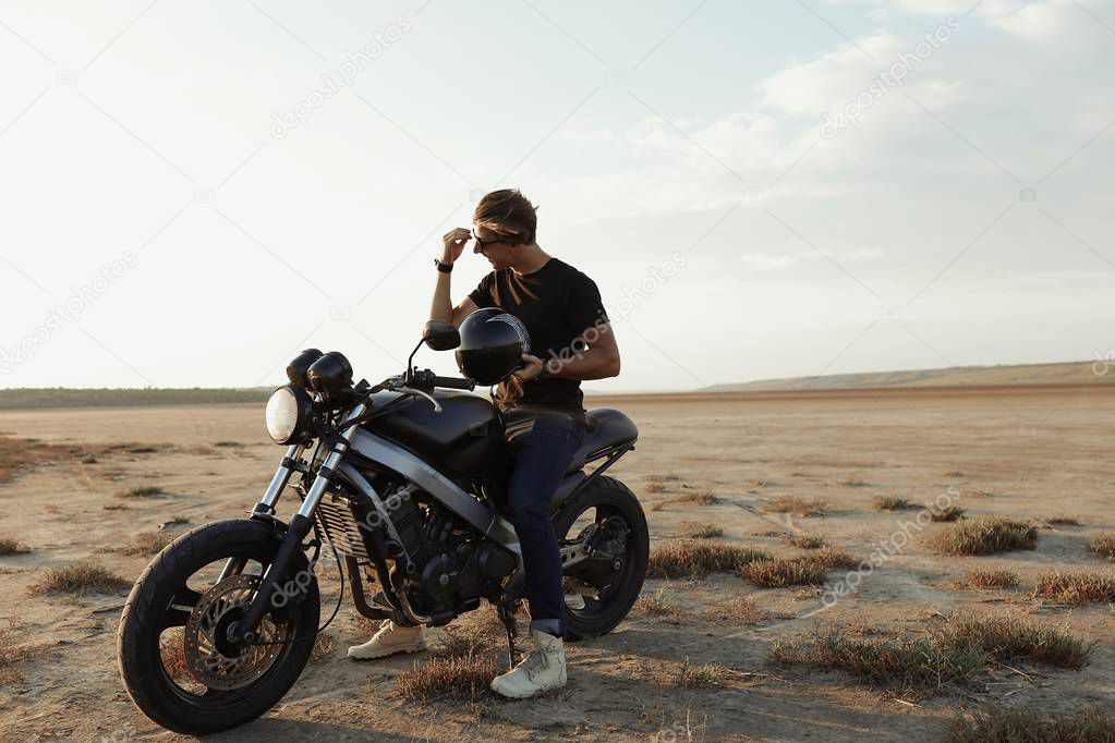 Young extreme driver on  the motorbike, in the middle of the desert, helmet with the wings, accessories, sun glasses, sand, tires, risky, free, outdoor, freedom of the soul, sunset, sport, relax