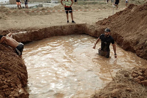 Brutal strong man in the pool with dirty water, wet, black sportwear, accessories, clay, racing, running, winner, contest