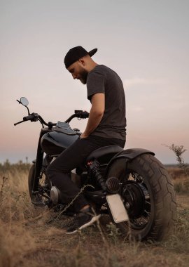 Motosiklet üzerinde oturan alanın ortasında yalnız adam düşünme road, seyahat, güçlü, özgür, kap kafa, çim üzerinde hakkında