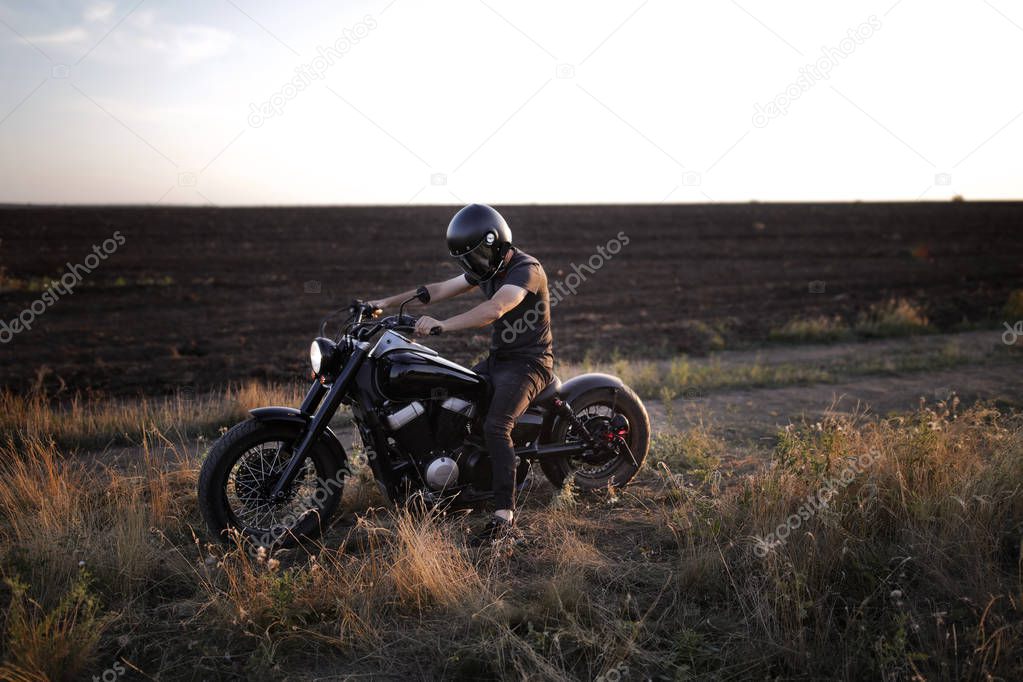 Racer  in the black helmet sitting on the motorcycle, on the field, alone, nobody else, sun set, free, strong, riding, extreme, sport, travelling