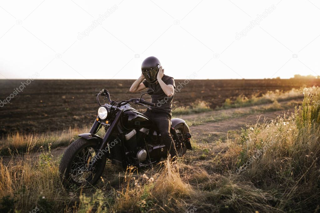 Male on the bike trying to put off the helmet, on the field,  travelling around the world, freedom, strength, tires, field, alone, motorcycle, beautiful sun set
