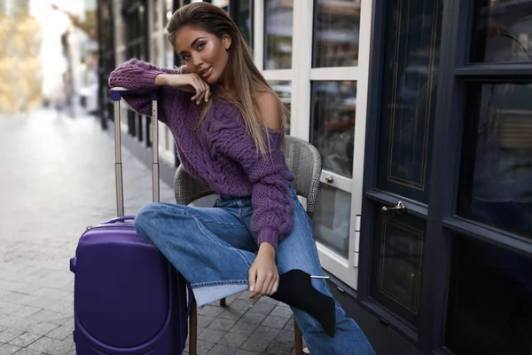 Pretty Model Purple Pullover Blue Suitcase Sitting Chair Cafe Jeans — стоковое фото