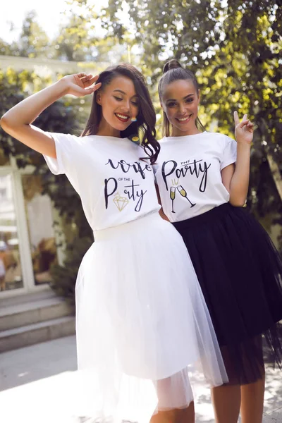 两个微笑的女孩在相同的白色 T恤衫 黑白相间的裙子 有乐趣 — 图库照片