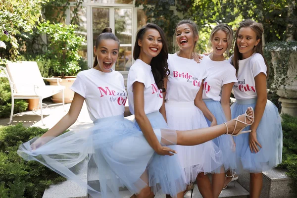 Smiling group of girls in the light blue skirts and white t-shirts with the title standing in the garden, restaurant , event, party, makeup, hair style, fashion, beauty, laughing, cheerful