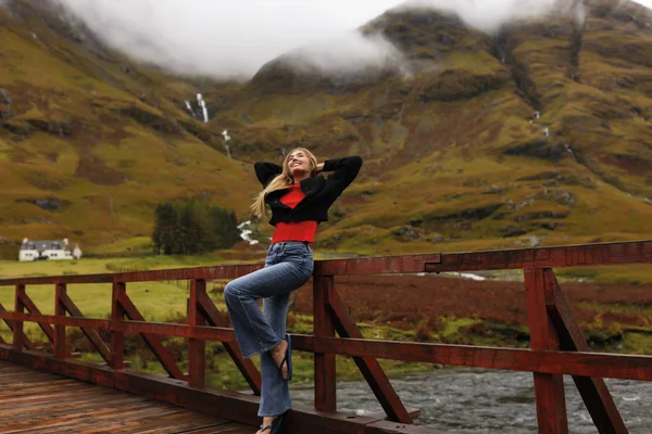 ハンズアップ 笑顔と幸せの旅行者 スポーツ 野生の自然 金髪の木製の橋の上に立っては空想若い女の子 — ストック写真