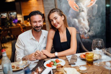 Birlikte akşam yemeği restoranda oturan güzel bir çift. Romantik bir atmosfer. Holding kadının ellerini dostum. Sevgi ve bakım.