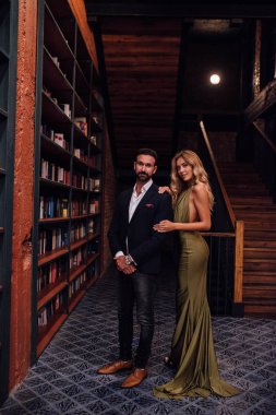 Güzel çift akşam takım elbise ve elbise birlikte ayakta giyinmiş. Lüks resim kitaplığı'nda çekim,.