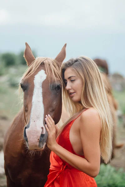 フィールド上の馬を持つ少女 女性は ロバを抱擁します 赤いドレスを着ています 周りの自然の風景 — ストック写真
