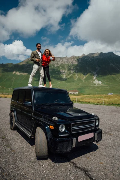 車の屋根の上に立って愛の人々 を抱き締めます 自動車でジョージアの周り旅行します 暖かい秋の日 — ストック写真