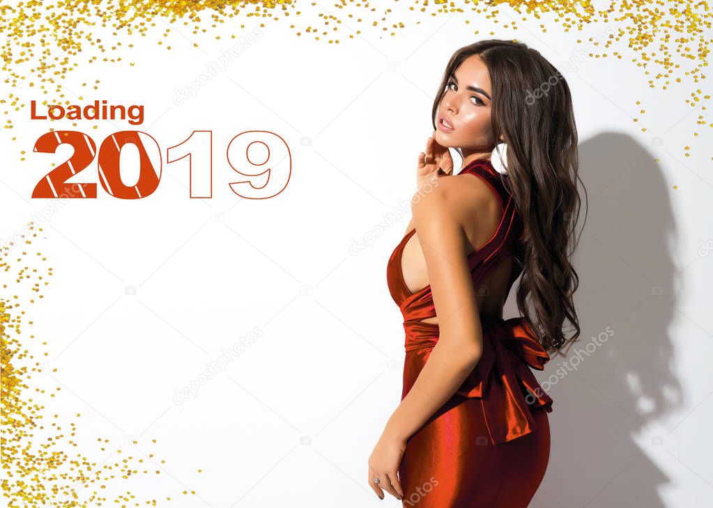 New Year picture for calendar or holiday card. Attractive lady in red dress with bow on the back. Golden sparkles.