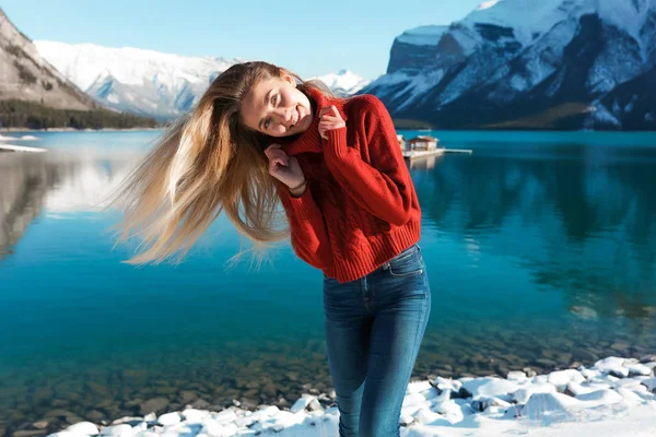 漂亮的女孩在冬日的湖面上玩得很开心 挥舞着头发 微笑着 背景上的雪山和蓝天 — 图库照片