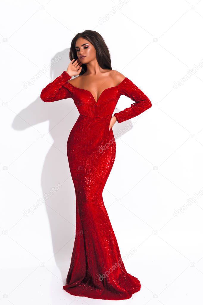 Tender lady in red dress with decollete ,open shoulders and sleeves. Hand near face. Bright stylish makeup.