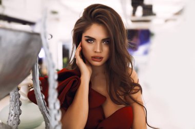 Tutku birim kıvırcık saç modeli, saç için omuzlarına düşme flört bayanla. Moda makyaj ve mükemmel bir görünüm. El yüz, ihale yumuşak deri, büyük dudaklar. Kırmızı kokteyl elbise parti için