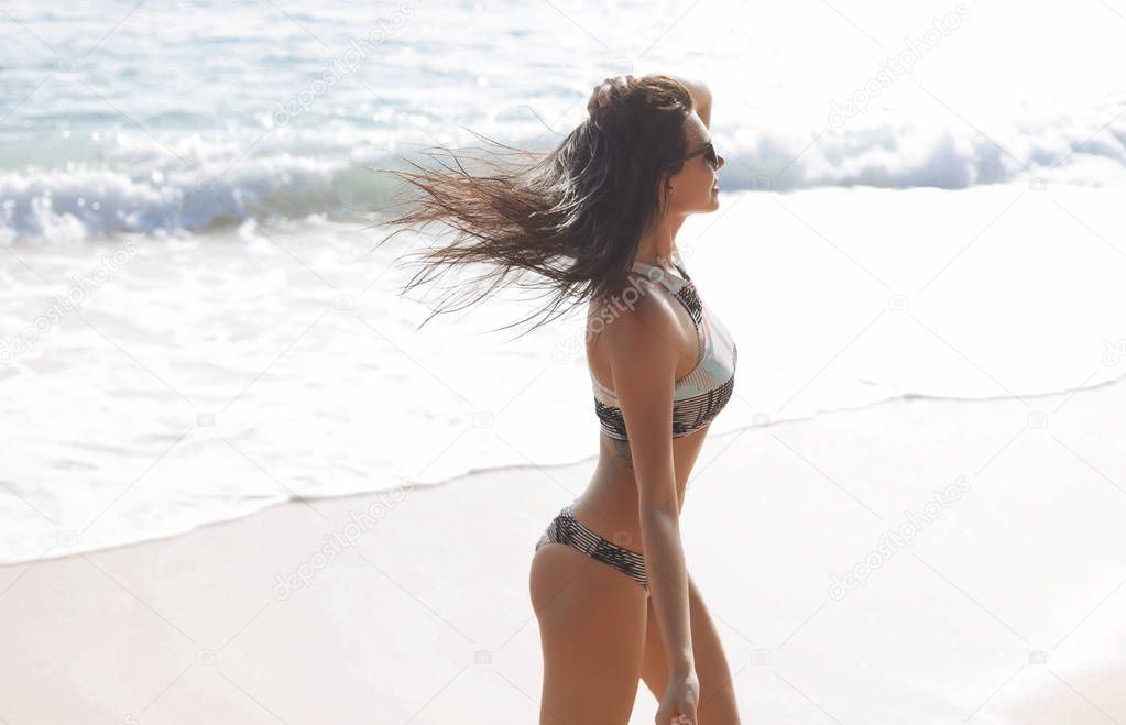 Mujer joven modelo en traje de baño en la costa del mar