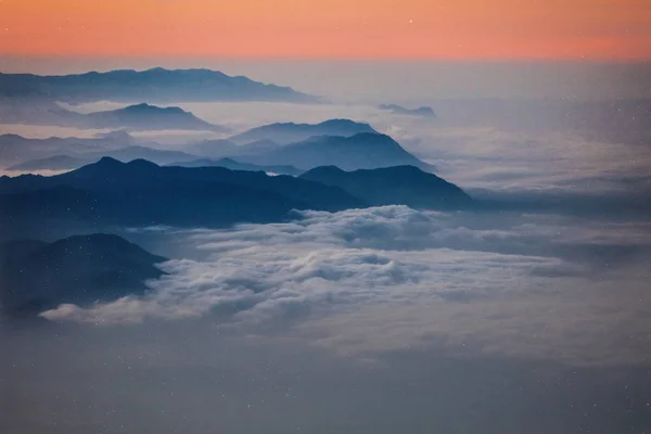 照片上是非洲日出时山的高山 乞力马扎罗 天空的红色和桃色 白云环绕着黑色的山脉 和平的沉默 巨大的高度 — 图库照片