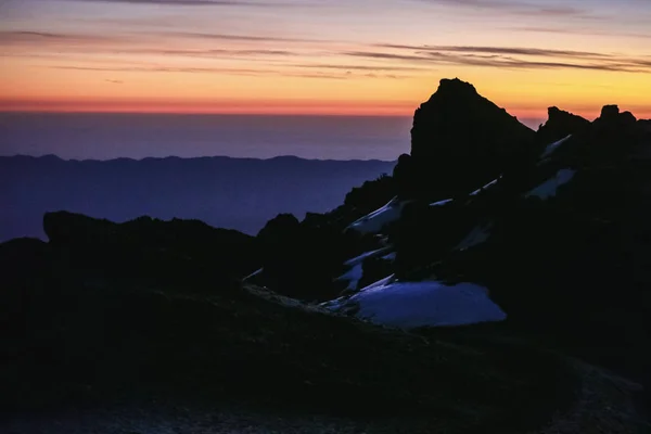 橙色明亮的天空 非洲山脉日出的壮丽景色 黑岩覆盖着白雪和晨雾 征服乞力马扎罗山 感受权力和自由 — 图库照片