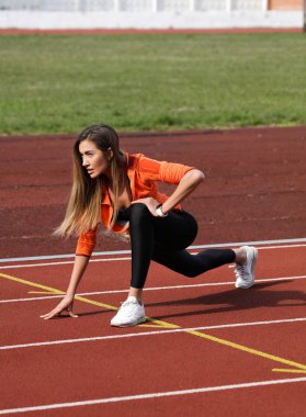 Pistte maratona hazırlanan aktif atlet. Bitirmek için ilk almak için germe ve ısınma kıtırma yapıyor. Şık ve rahat leggins ve spor ayakkabı giyiyor. Kazanmaya odaklanmış. Mükemmel gövde