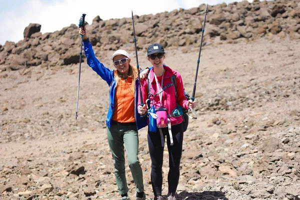 スポーツの2人のかわいい女の子は 登山のためのすべての機器で山の上に立って着用します 植物や木はありません アフリカの危険で極端な冒険 快適な靴 スティックを保持 — ストック写真