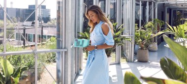 Açık mavi elbisesi ve aksesuarlarıyla mükemmel bir vücut. Elinde bir kitap tutuyor, okuyor. Sarışın, gür saçlı, şık görünüşlü, yüzünde makyaj var. Yaz sıcağı