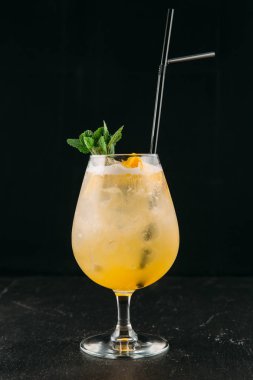 Nane ve turuncu siyah arka planlı sarı alkol kokteyli.