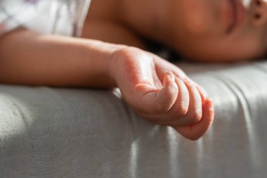 Kanepenin kenarından sarkan bir çocuğun makro detayı.